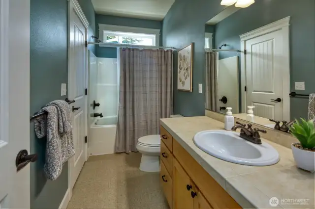 This upper-level full bath features a tub and shower combo, large vanity with ample storage—perfect for guests or secondary bedrooms, with a transom window adding soft natural light.