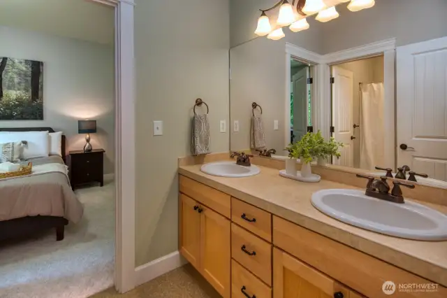 Jack-and-Jill bathroom features dual sinks, a full-length mirror, and private shower access—ideal for sharing while maintaining comfort and privacy.