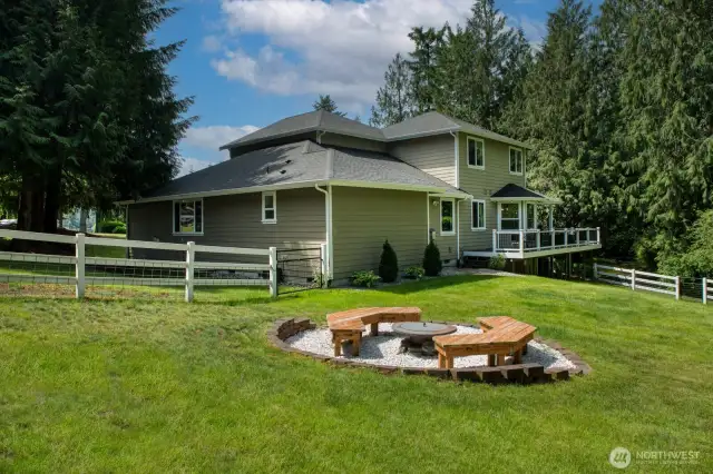 Enjoy the beauty of the Pacific Northwest in this expansive backyard, featuring a charming built-in fire pit with custom-built bench seating—perfect for evening gatherings under the stars.