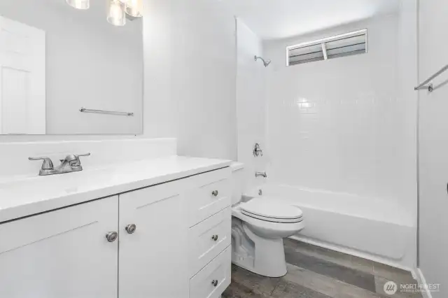The shower/tub combo is fully tiled in the full bathroom with new vanity, counter, mirror, lighting, and toilet. Beautiful!