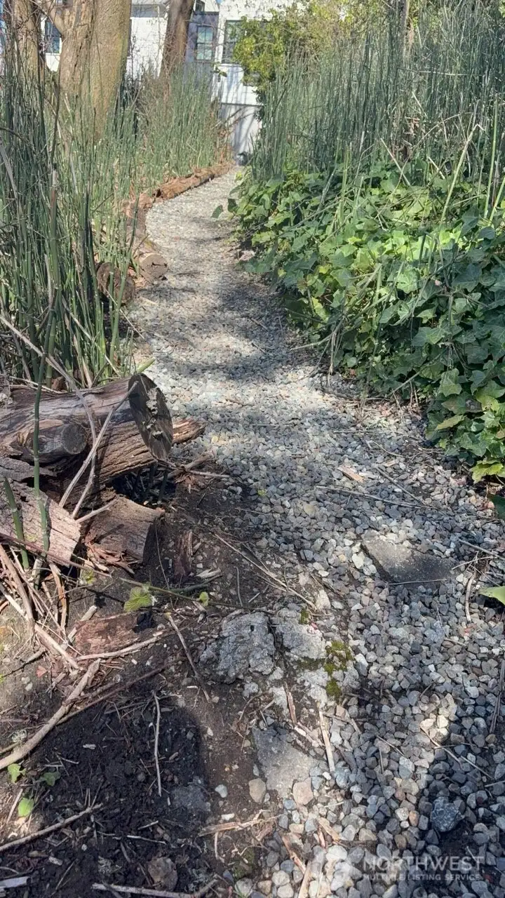 Asphalt tab leads to gravel pathway , allows one to traverse the front side of the lot.