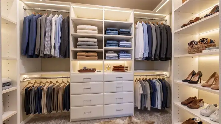 Primary walk-in closet featuring an array of storage drawers, and dedicated open shoe shelving. This photo is virtually staged.