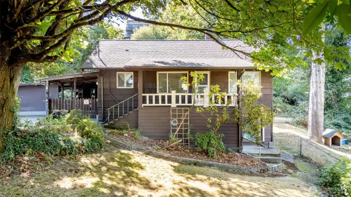 The covered front porch has stood the test of time and remains in good condition, offering a welcoming spot to sit back and enjoy the surrounding trees. In the fall and winter, when the leaves have dropped, you’ll even catch a filtered view of the water peeking through the branches, a reminder of how close you are to both nature and the shoreline.
