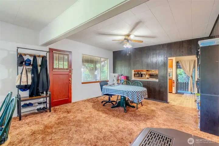 The ceiling fan and the surrounding trees work together to help keep the home comfortable on warm days. Large windows throughout the space let in plenty of natural light, creating a bright interior. At the far end of the house, a sliding glass door provides direct access to the driveway for everyday convenience.