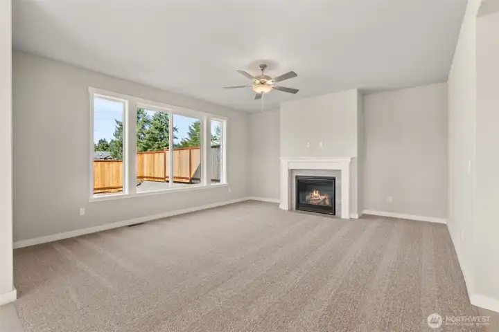 Large living room features a gas fireplace to stay warm on cooler evenings and a ceiling fan to stay comfortable throughout the year.
