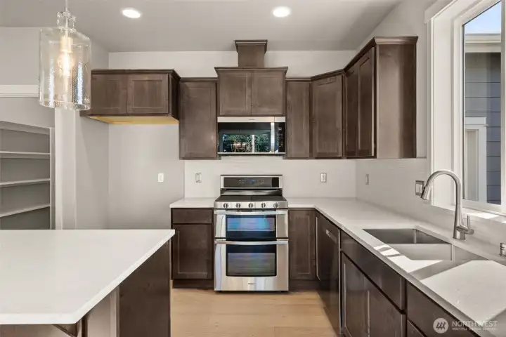 Beautiful Charcoal-stained maple cabinets, quartz counters and full backsplash make this kitchen a stunner! Gas range/double oven is standard!