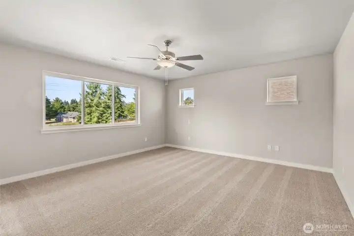 Spacious primary bedroom features ceiling fan for added comfort and great natural light from windows