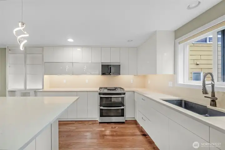 A sleek, thoughtfully designed kitchen showcases quartz countertops and a matching quartz backsplash, creating a seamless and elevated look. Every detail is carefully considered, blending modern style with functional design for a space that is both beautiful and highly practical.