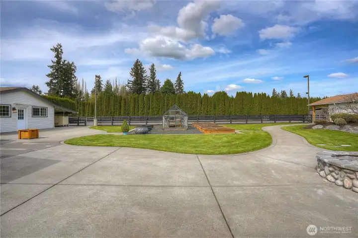 The magnificent back courtyard & grounds offers a sweet garden area complete with greenhouse, planters and raised garden beds. Beyond under the carport to the left you will notice the 50KW propane generator, this unit conveys with the property