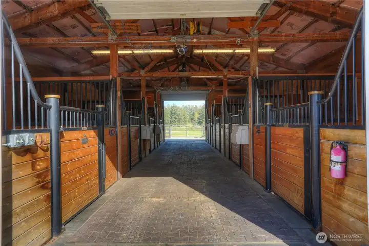 Eight stall show barn with custom stall fronts with T&G, matted stalls, Nelson water system, paver aisle, dual access to barn aisle, tack room and feed & hay storage. Back pastures are beyond