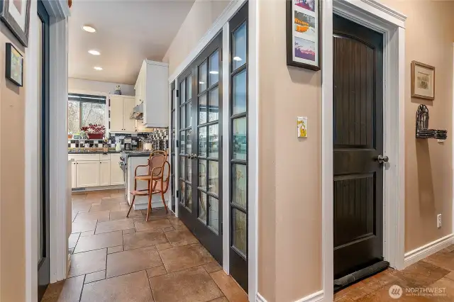 Back down on the main floor. Another entrance to the kitchen from the main entryway with walk-in pantry. The windows have been walled-off on the other side of the French doors for a secondary living space. Can be accessed through the doorway in the hall.
