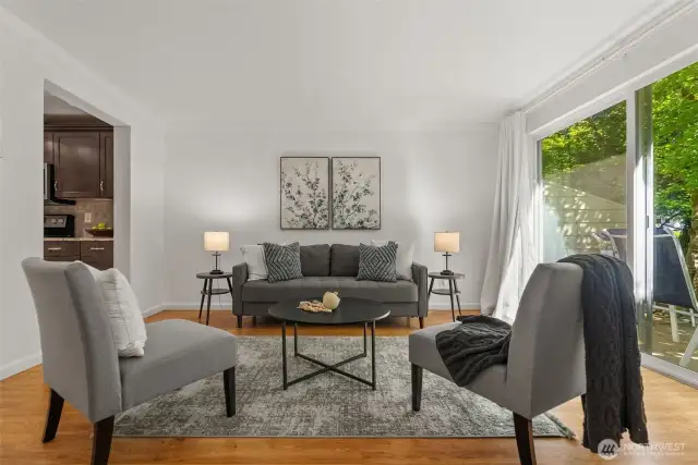 Sliding glass doors lead to an adorable patio, surrounded by lush greenery that makes it a perfect spot for relaxing or entertaining.