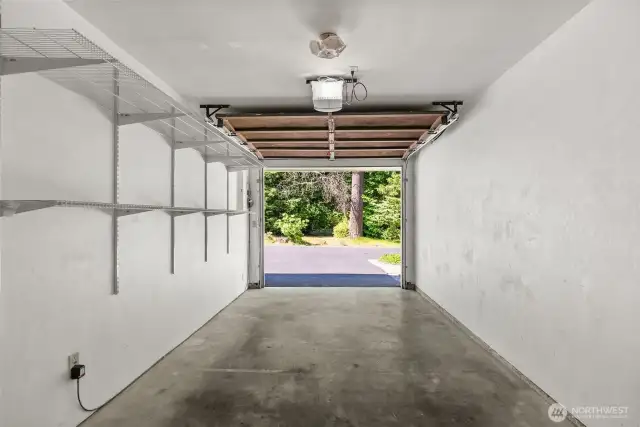 The garage comfortably parks one car and includes built-in shelving, perfect for organizing tools and storage.