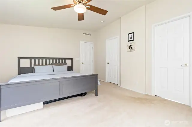 Primary bedroom with ceiling fan and doors to the en suite bath and walk-in closet.