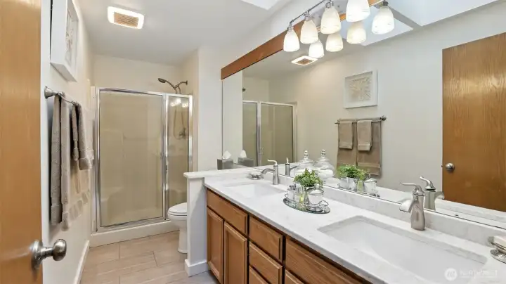 The primary bath has a dual vanity with quartz countertops and tile flooring.