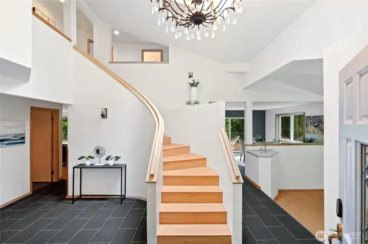 The gorgeous and spacious entry features a grand curving staircase ~ it opens to the step-down formal living room on one side and the family room on the other....