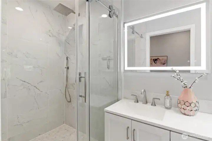 This stunning en suite bath features an oversized rain shower and specialized fog-free, lit mirror.