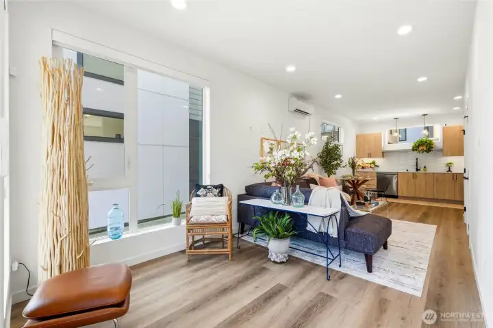 Open main living area with wide-plank flooring, recessed lighting, ductless HP-mini split and large windows providing natural light.