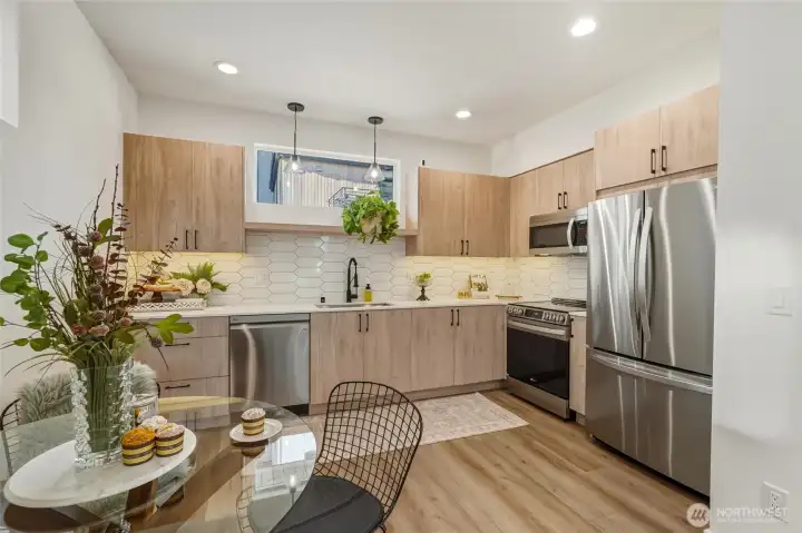 Contemporary kitchen with flat-panel wood cabinetry, under cabinet lighting, stainless steel appliances, and white quartz countertops.