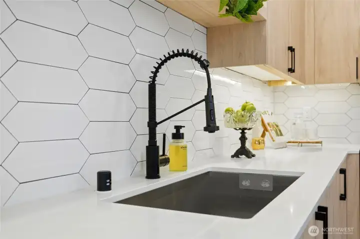 Detail of kitchen workspace with hex tile backsplash, undermount sink, and matte black pull-down faucet.