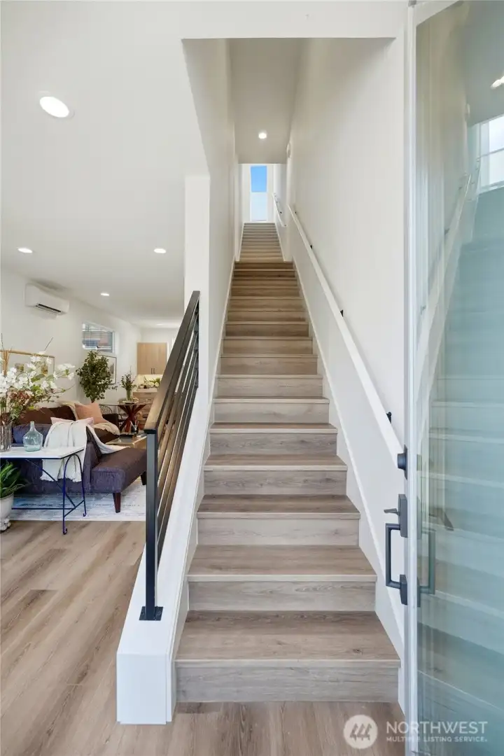 Contemporary stairwell with wood-style treads, modern railing, and recessed lighting.