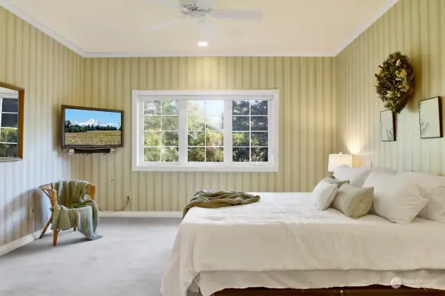 The primary bedroom exudes tranquility with its calming green color scheme and a ceiling fan, creating a peaceful and soothing atmosphere.