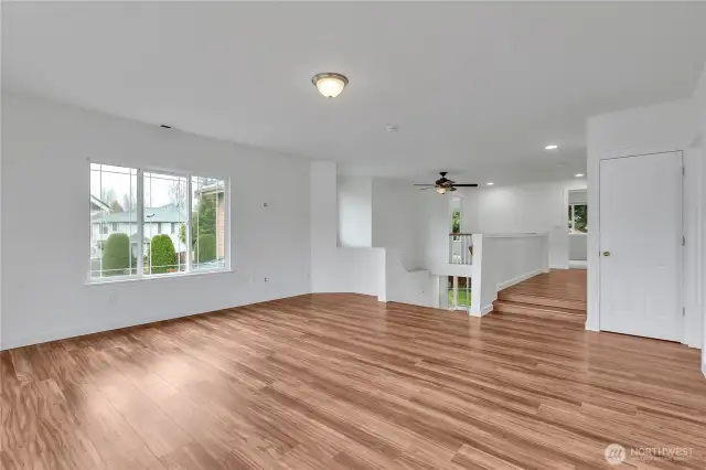 The great room has large windows that let natural light flow in and has beautiful wood floors.