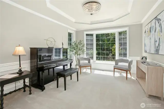 Step into the formaldining space or music room, where a coffered ceiling adorned with a sparkling chandelier adds a touch of sophistication. The bay window invites sunlight to spill across the room, creating the ideal space for quiet reflection or an intimate recital. Crisp white wainscoting continues the classic design, seamlessly tying together the elegance of this inviting space.