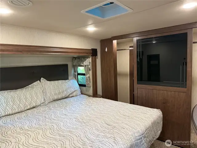 King sized bed and large full width closet with lighting and shelving.