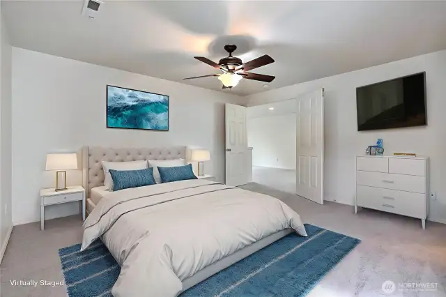 Primary bedroom suite has double doors and ceiling fan.