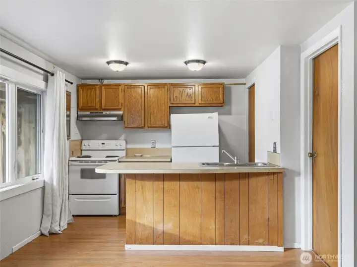 Kitchen, lliving area combo with a bar space for eating.