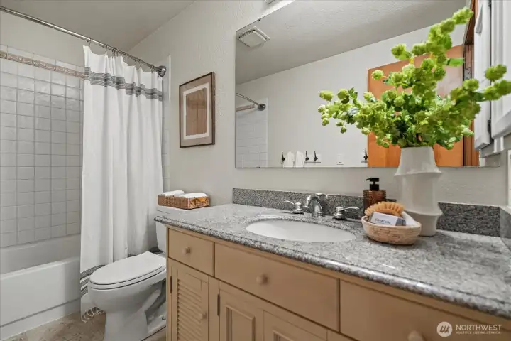 Spacious hall bathroom featuring a tub and oversized vanity, ideal for household use.