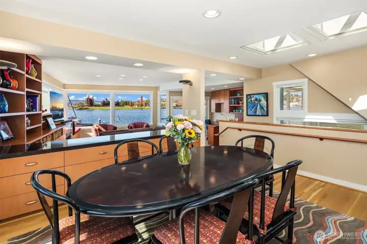 A credenza grounds the elevated dining room, with skylights above and the Gas Works Park view cut into the far wall like a living painting.