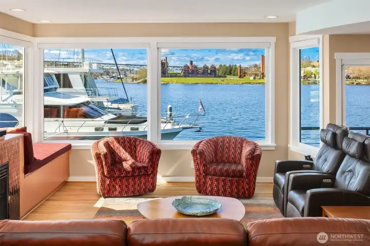 Corner windows wrap the living room in water and sky; a built-in window seat with storage runs beneath the glass.