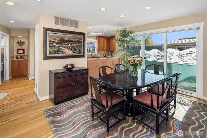 The dining room opens through sliding glass to a small "bistro" deck framed by custom glass fish artwork that serves as a privacy panel — the kind of detail you only get in an architect-designed home.