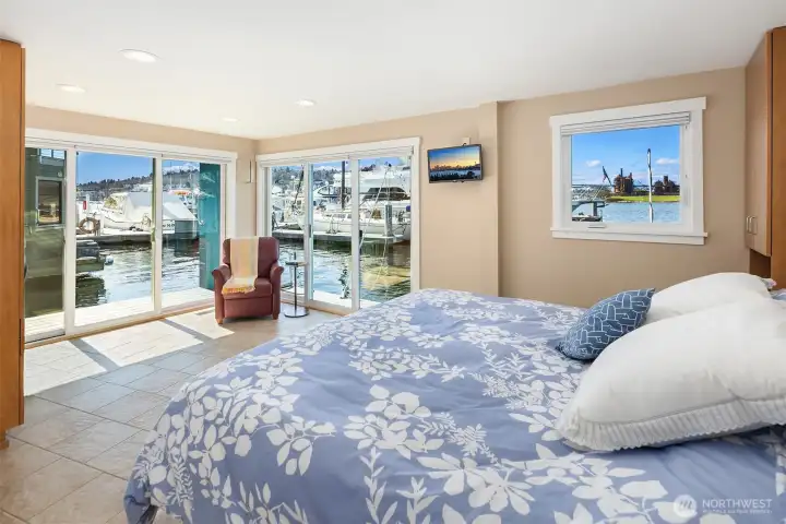 The primary suite with its built-in king captain's bed, two sets of sliders to private boat decks, and a Gas Works view from the pillow.