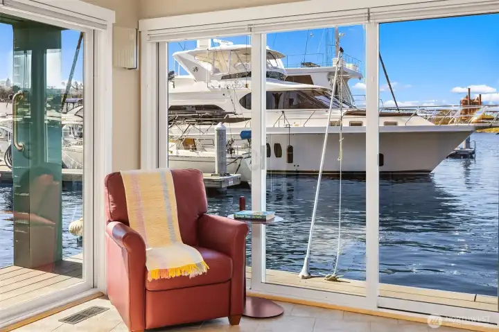 In the primary suite, sliding doors frame a neighboring yacht, and a reading chair catches the late-afternoon light.
