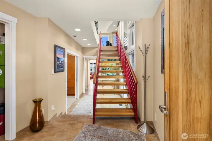 The entry: tile floors, a beautiful solid wood front door, and the staircase pulling you up to the view from the living room.