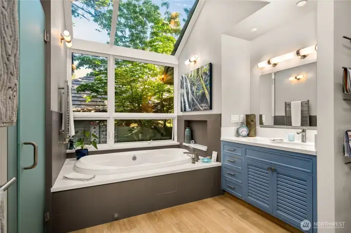 Primary bathroom with soaking tub and views of the sky