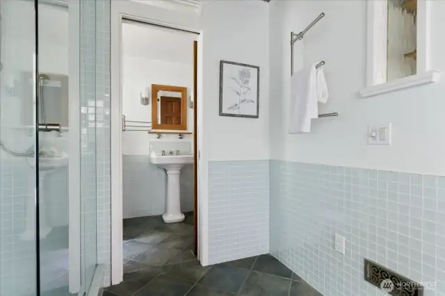 Looking through to pedestal sink and toilet with pocket door between.