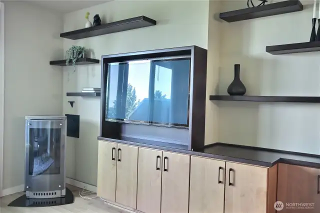 Living room has many build-in cabinets, gas fireplace unit.