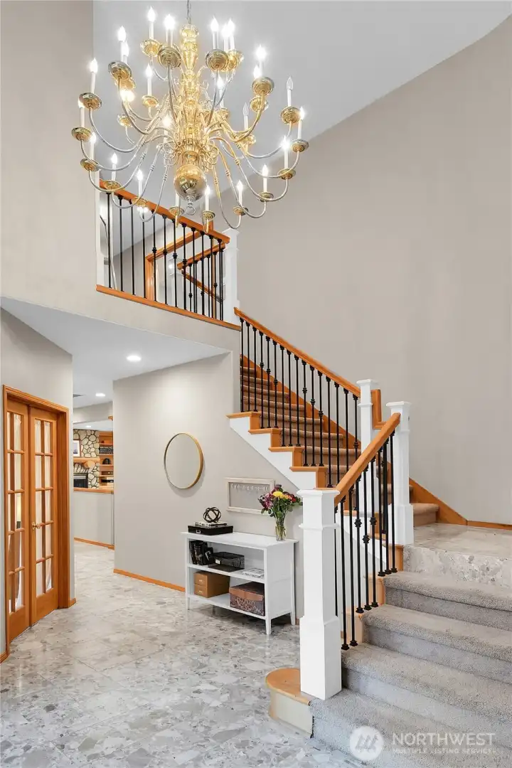 Dramatic foyer with marble floor, vaulted ceilings, and grand staircase