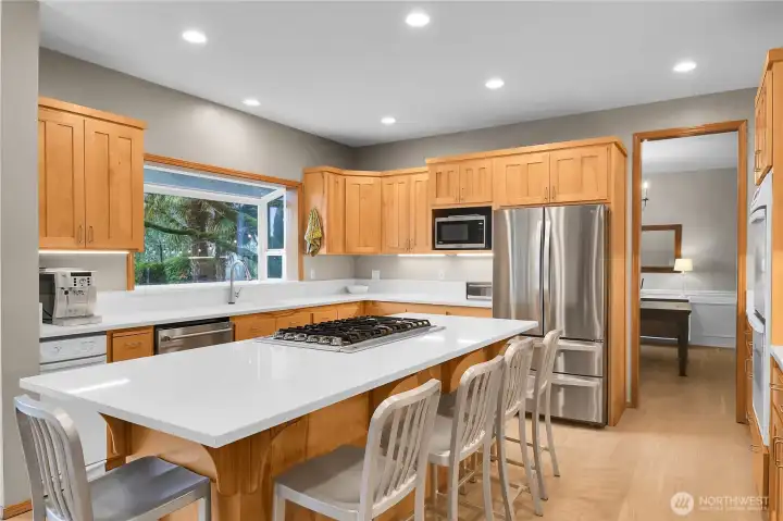 Open concept kitchen with white quartz counters, oversized island, eating area, and LVP flooring