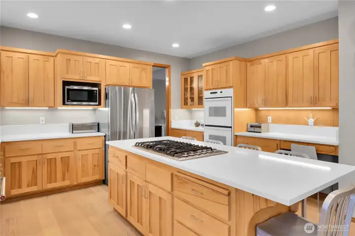 Open concept kitchen with white quartz counters, oversized island, eating area, and LVP flooring