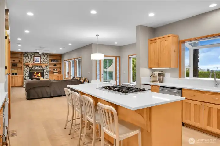 Open concept kitchen with white quartz counters, oversized island, eating area, and LVP flooring