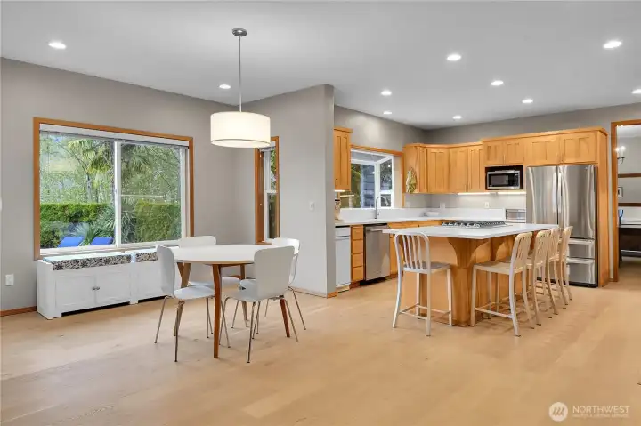 Open concept kitchen with white quartz counters, oversized island, eating area, and LVP flooring