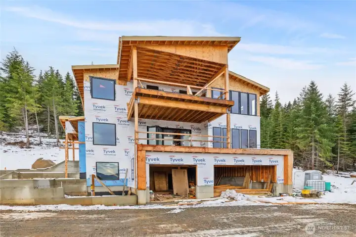 Garage side of home looking at the Stuarts.  1652 sq ft garage.  Deck off living room on main level and primary bedroom on top level.