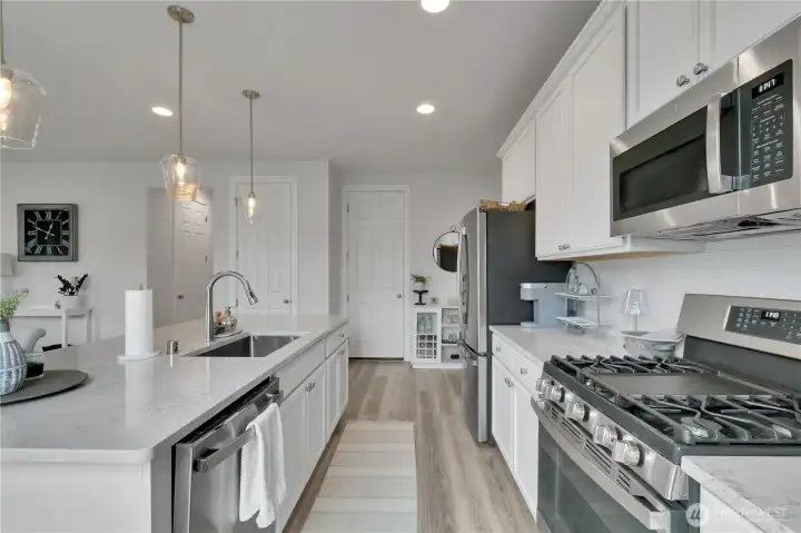 Perfect kitchen for entertaining, large island & beautiful quartz counters, 5 burner gas stove, & counter-depth stainless steel refrigerator.