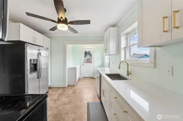 Brand new kitchen cabinetry, quartz countertops, and sink! Door to the backyard at the end of the kitchen