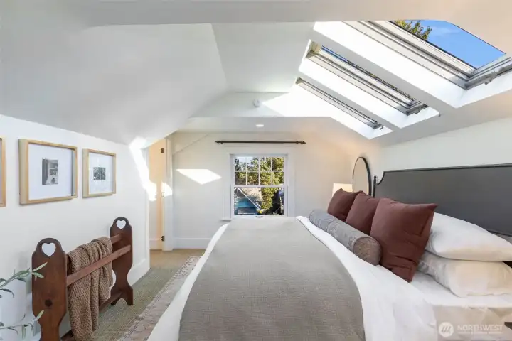 Upstairs are 3 bedrooms, including this skylit primary. King bed shown here.